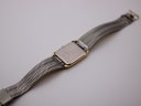 View of the watch from the underside, showing the stainless steel case back and the mesh-style inner surface of the integrated bracelet.