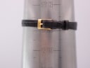 Close-up of the brown leather strap with a gold-tone pin buckle on a wrist sizing gauge, indicating a maximum wrist circumference of 165mm / 6.5 inches.