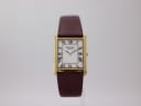 Front view of gold Raymond Weil rectangular watch with white Roman numeral dial and brown leather strap.