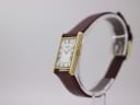 Angled side view of the Raymond Weil watch showing the gold case and crown on a display stand.