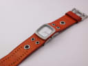 Top-down view of the Nixon watch and full length of the brown leather cuff strap.