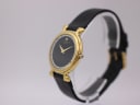 Side angled view of the Raymond Weil watch showing the gold plated case, crown, and black leather strap on a stand.