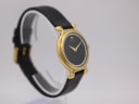Another side angled view of the gold Raymond Weil watch on a stand, highlighting the case profile and strap.