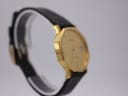 Angled side view of the gold octagonal Bulova watch on a clear display stand.