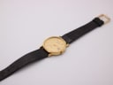 Full length view of the Bulova watch with its black leather strap and gold-tone buckle.