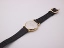 Angled rear view showing the watch's stainless steel case back and black leather strap.