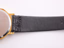 Detailed close-up of the black leather strap's crocodile-effect texture near the watch case.