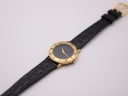 Overhead view of the Gucci watch laid flat, displaying the black crocodile-effect leather strap and gold-toned buckle.