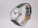 Angled side view of the Mondaine watch showing polished silver case and red signed crown.