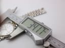 Digital caliper measuring the watch case diameter, showing a precise reading of 34.17mm on the display.
