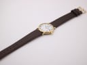 Overhead view of the Raymond Weil watch on its brown leather strap, laid flat.