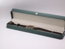 The Raymond Weil watch presented in a generic green leatherette display box with a small gold crown emblem.