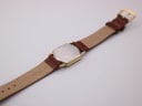 View of the case back and the underside of the brown leather strap, showing 'Genuine 18' marking for lug width.