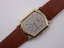 Close-up front view of the Seiko watch dial, showing the silver face, small seconds, and gold hands.