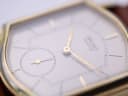 Extreme close-up of the Seiko watch crystal, showing visible scratches and gold hands.
