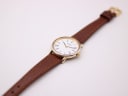 Overhead view of the Tissot watch with its full brown leather strap laid flat, displaying the gold-tone buckle.