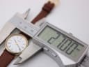 Digital caliper measuring the Tissot watch case, displaying a precise diameter of "27.00 mm".