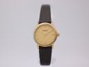 Front view of the gold Tissot C226K dial with minimalist baton indices and brown leather strap.