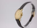 Side view of the Tissot watch showing the gold-tone case and crown, with brown leather strap.