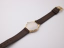 Rear view of the watch on the strap, showing the case back and full length of the brown leather strap.