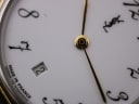 Extreme close-up of the white dial, showing the YSL logo, stylised numerals, date window at 6, and "Made in France" text.