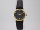 Front view of Raymond Weil 9923 gold electroplated watch with black dial and stone-set markers on a black leather strap.