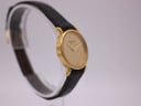 Another angled side view of the Raymond Weil 710 watch, highlighting the dial and the curved lugs of the gold case.