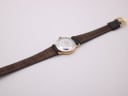 View of the watch from above, showing the stainless steel case back and the full length of the black leather strap.