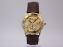 Front view of a gold-tone Accurist skeleton automatic watch with a brown leather strap.