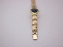 Full length top-down view of the gold tone Raymond Weil watch and its integrated bracelet.