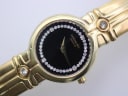 Another side profile view highlighting the gold tone case and integrated bracelet on a display stand.