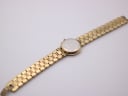View of the watch back and extended bracelet, showing the stainless steel case back with engravings and the gold-tone bracelet.