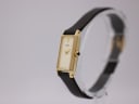 Angled side view of the Seiko watch, showing the gold-tone case and crown with a blue cabochon accent.
