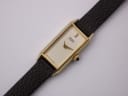 Close-up front view of the Seiko watch dial, showing the cream face, gold baton marker, and hands.