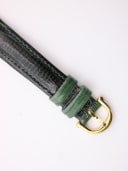 Close-up of the green lizard-effect leather strap end with a gold-tone pin buckle.