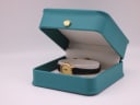 The Raymond Weil 5717 watch nestled inside a generic green leatherette presentation box, a common studio prop used for photography.