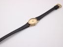 Top-down view of the entire Raymond Weil 5717 watch, extended on a flat white surface, showcasing the full length of the black leather strap and gold buckle.