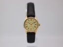Front view of Zenith quartz watch with champagne dial and gold case on a clear stand.
