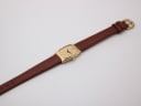 Overhead flat lay of the Raymond Weil watch showing the full length of the brown leather strap and gold case.