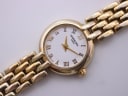 Angled close-up of the Raymond Weil watch dial, highlighting the textured white face and gold-tone bracelet.