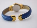 Back view of the blue textured leather bangle strap, showing the gold-tone end caps and the open bangle style.