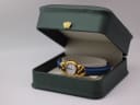 The Fontenay watch displayed inside the generic green leatherette presentation box, showing the watch face up on its blue strap.