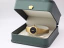 Zenith gold-tone watch displayed open in a generic green leatherette presentation box with a gold crown emblem.