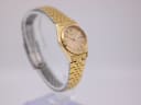 Another angled side view, capturing the slim profile of the watch and its integrated gold-tone bracelet.