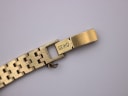 Close-up of the gold-plated integrated steel bracelet clasp, clearly showing the "SEIKO" engraving and safety chain.