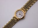 Overhead close-up view of the Seiko watch dial and part of the gold-tone bracelet, showing Roman numerals and "SEIKO QUARTZ" text.