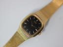Close-up top-down view of the gold tone Seiko watch dial, showing the minimalist black face with gold baton indices.