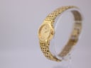 Angled side view of the gold Seiko quartz watch on a clear display stand, highlighting the case and bracelet profile.