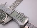 Digital caliper measuring the watch case diameter, displaying 37.46mm.