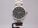 Front view of Seiko Sapphire Day-Date watch with black dial, gold baton indices, and two-tone steel bracelet.